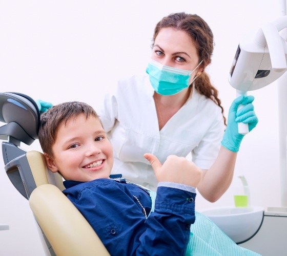 Young boy giving thumbs up in dental chair