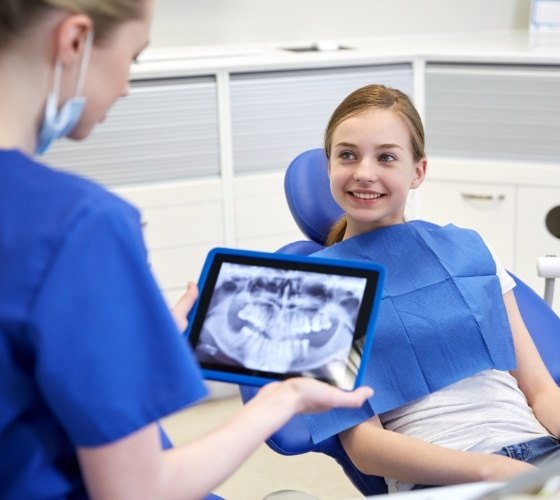 Pediatric dentist holding tablet with digital dental x rays of a child patient