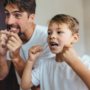 Man and his son flossing their teeth 