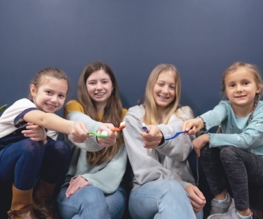 Four kids holding toothbrushes in pediatric dental office