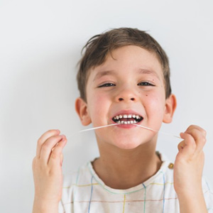 Little boy flossing between his teeth 