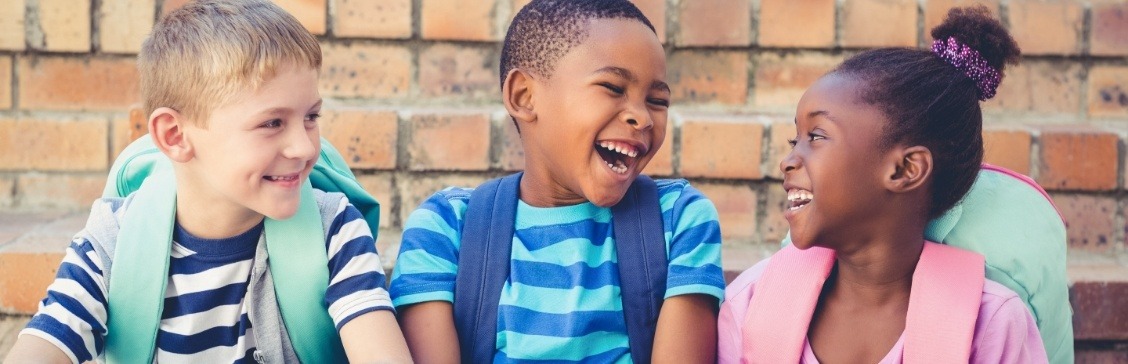 Three laughing kids wearing backpacks