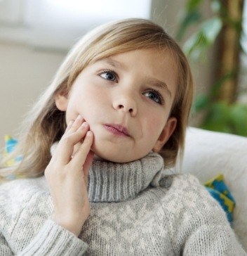 Young girl holding her cheek in pain