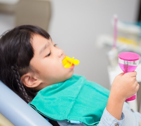 Child receiving fluoride treatment from pediatric dentist