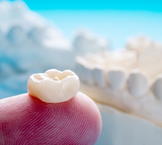 Pediatric dentist holding dental crown on their finger