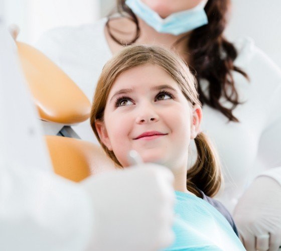Young girl in dental chair smiling at her pediatric dentist