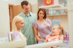 Little girl and parents at pediatric dentist