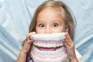 Young girl holding large model of teeth