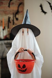 Child in ghost costume holding a candy bucket