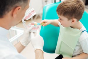Young boy at dentist practicing brushing teeth