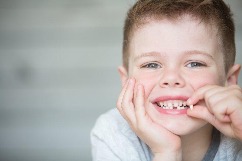 little boy holding a lost tooth